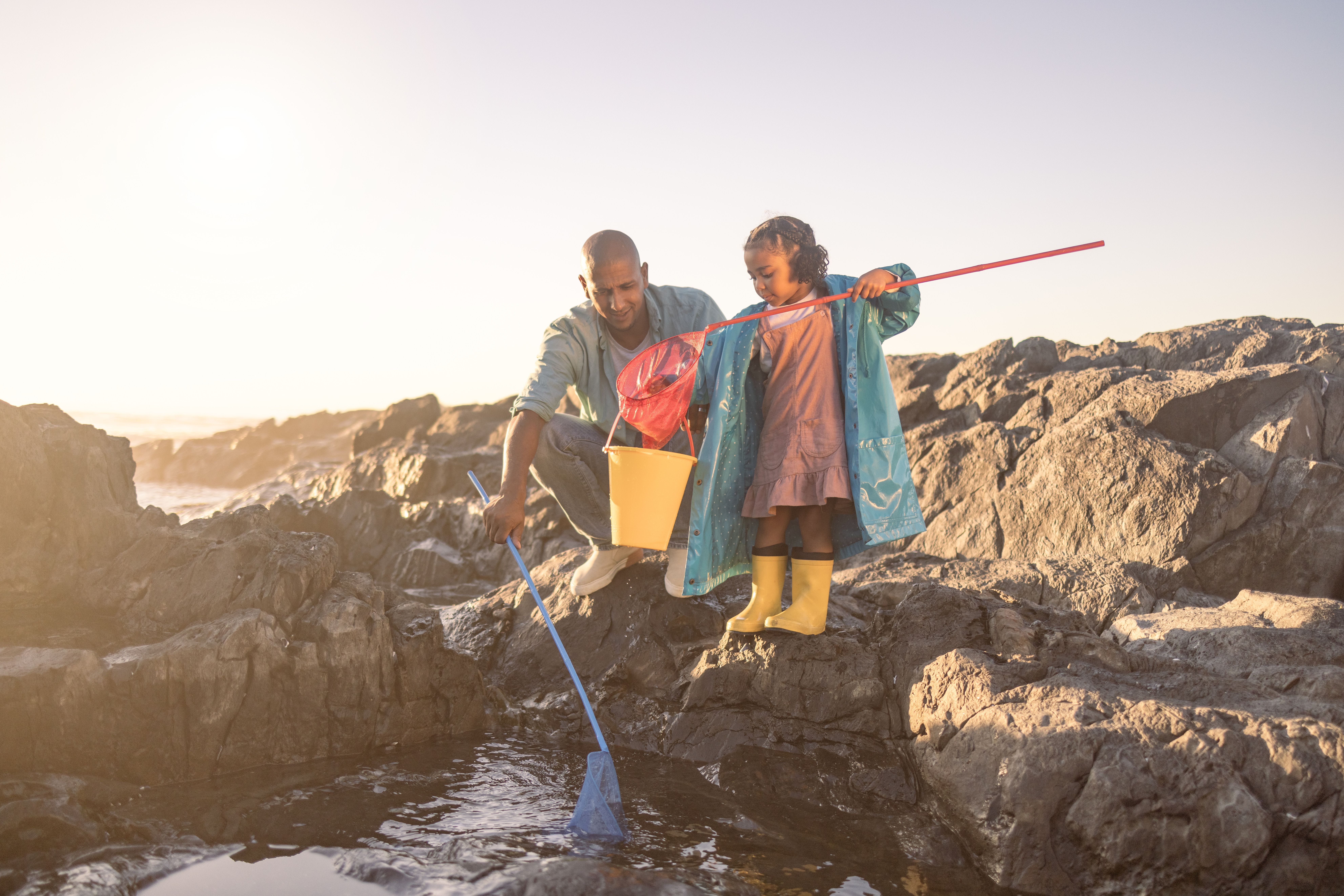 A father and child fishing on the beach near their RV campsite, enjoying casual outdoor RV travel experiences.
