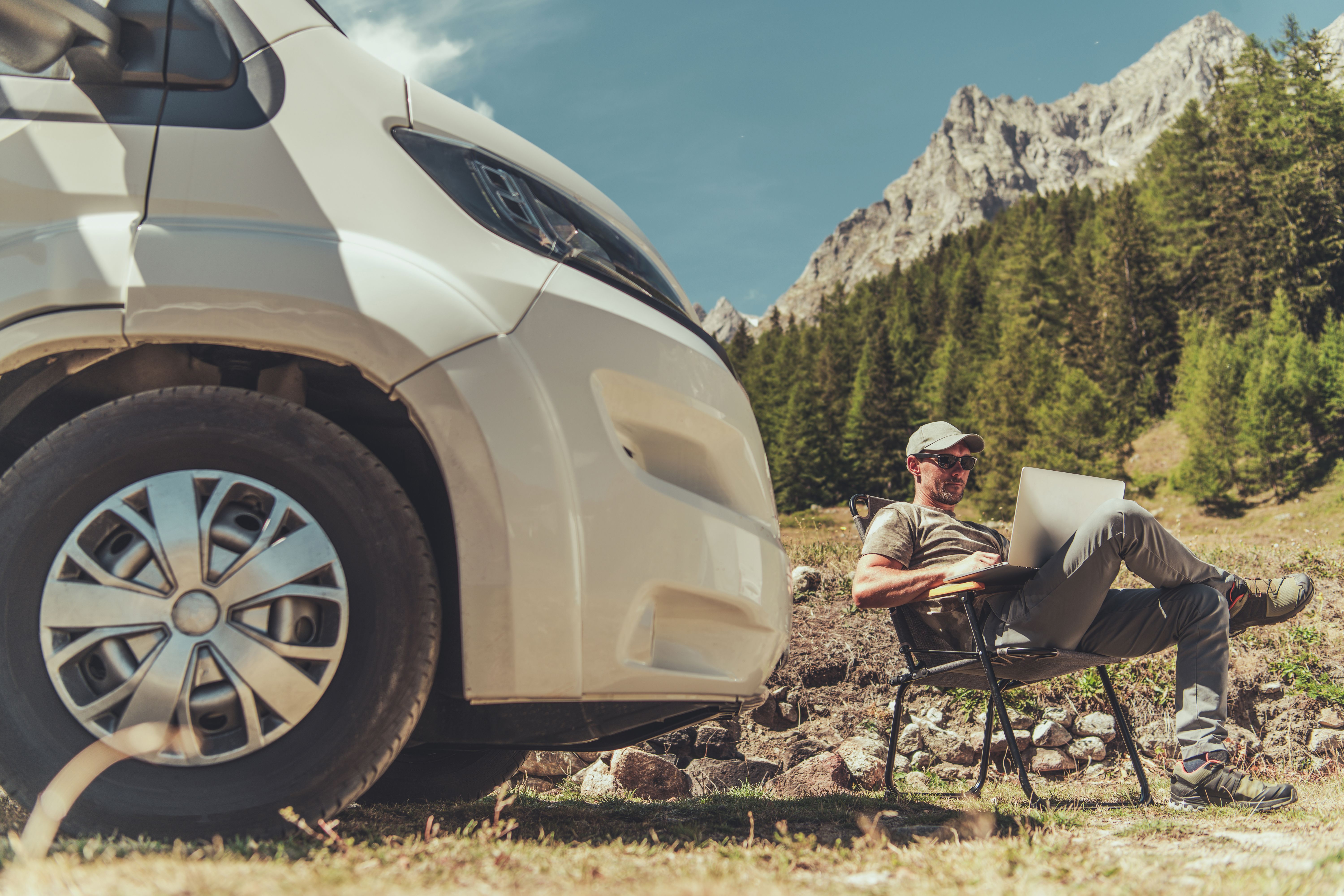 A man working remotely near his RV while boondocking off-grid, showing the balance of work and outdoor adventure.