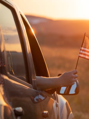 arm-holds-american-flag-from-car-at-sunset.