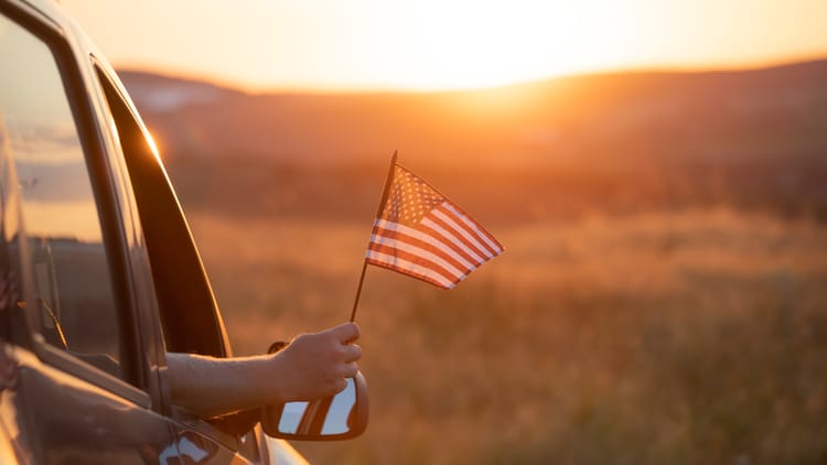 arm-holds-american-flag-from-car-at-sunset.