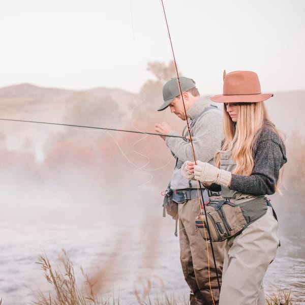 a luxury rv couple fly fishing on the riverbank tying flies